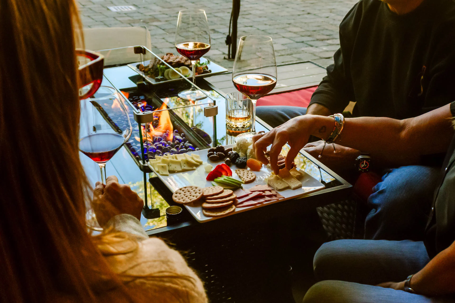 People enjoying wine and food outdoors by a cozy fireplace at Side Door Wine Bar & Café in Mammoth Lakes.
