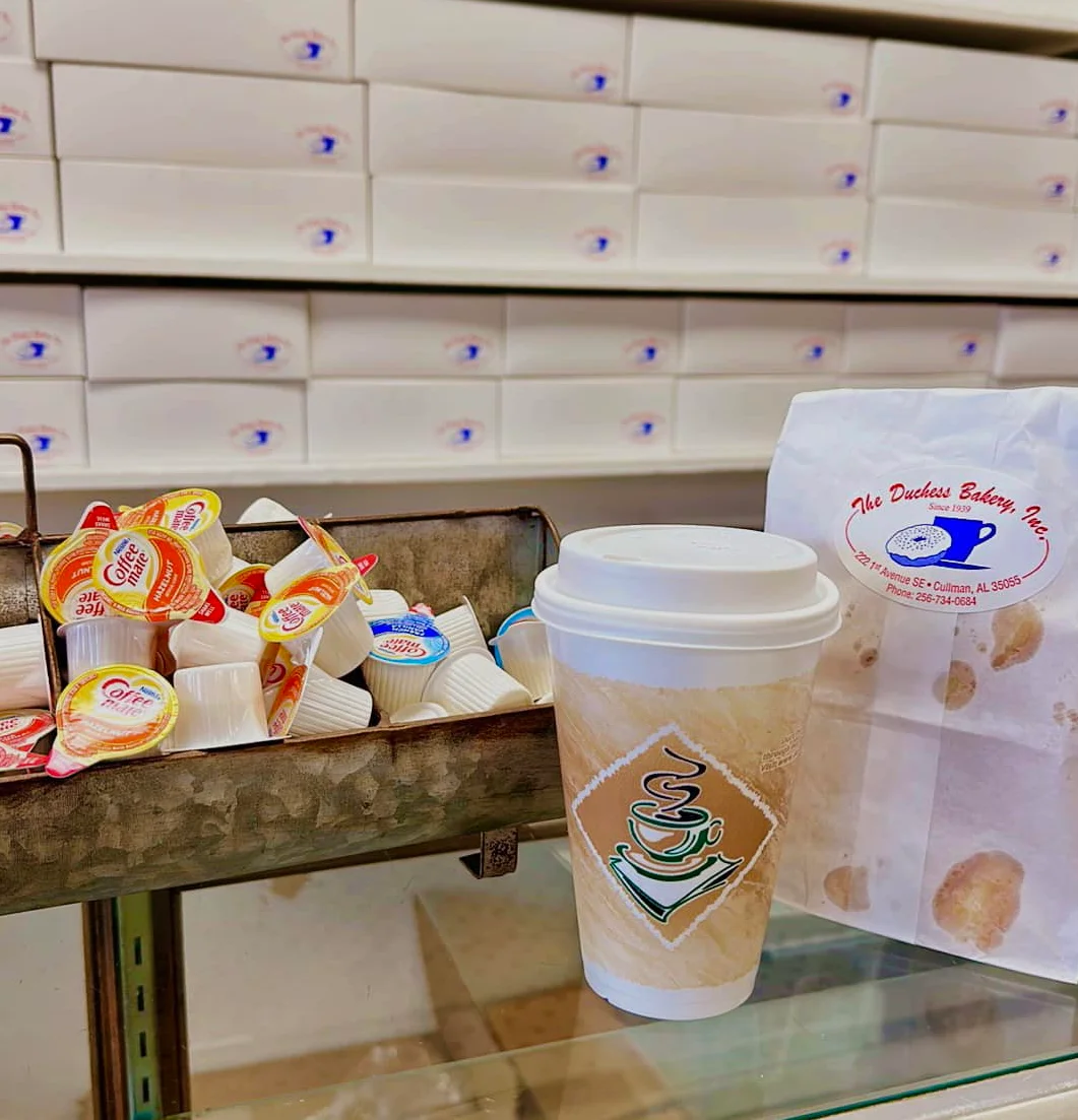 Coffee cup and creamers at a bakery counter