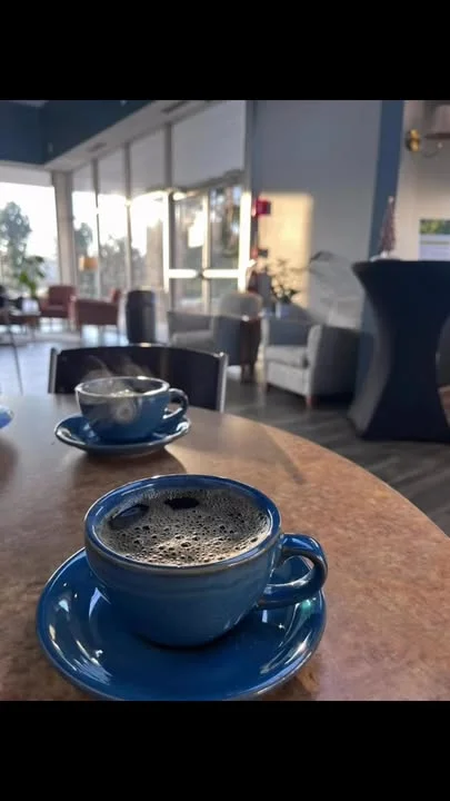 Two blue coffee cups on a table in a cozy cafe setting