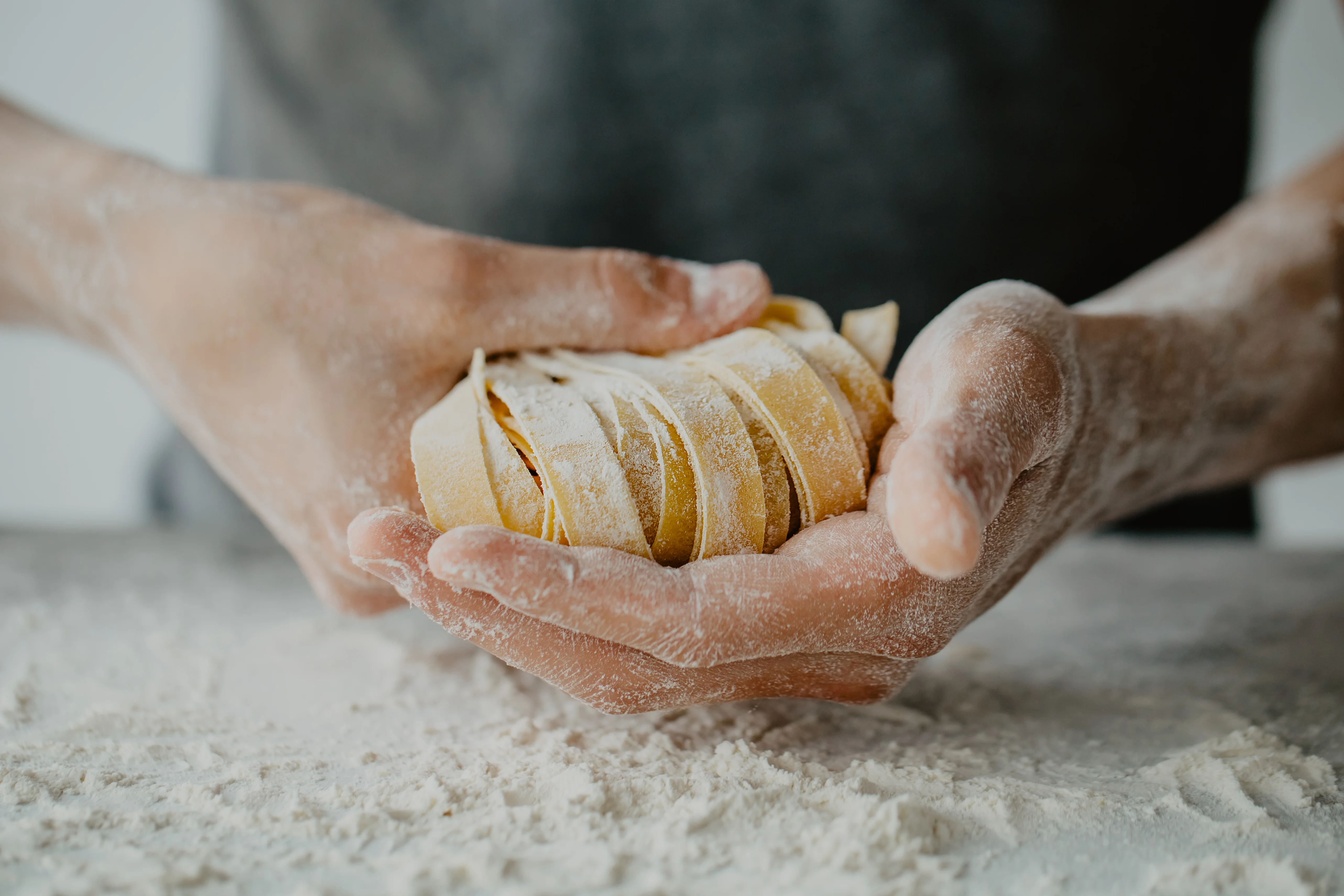 Freshly made Italian fettuccine pasta in hands