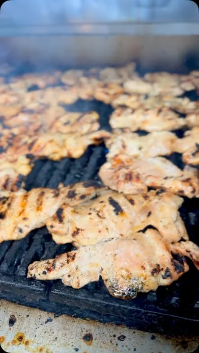 Grilled chicken pieces on a grill, showcasing a variety of cooked textures and char marks.