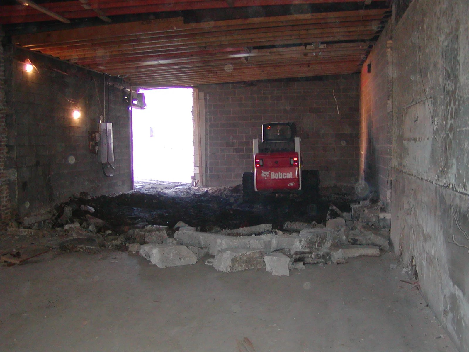 Construction site with machinery and debris in a spacious interior