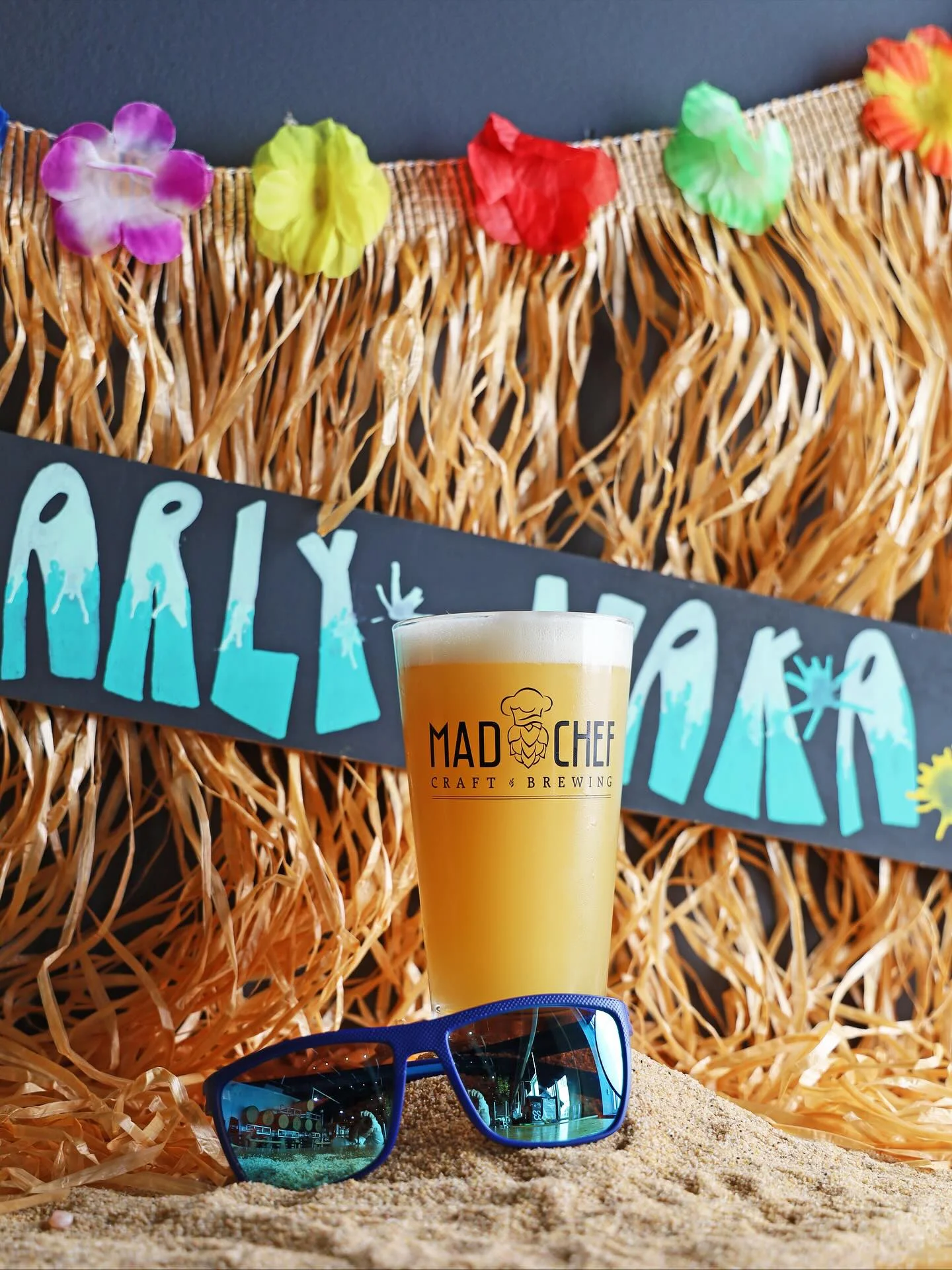 Craft beer in a glass with tropical decor and sunglasses