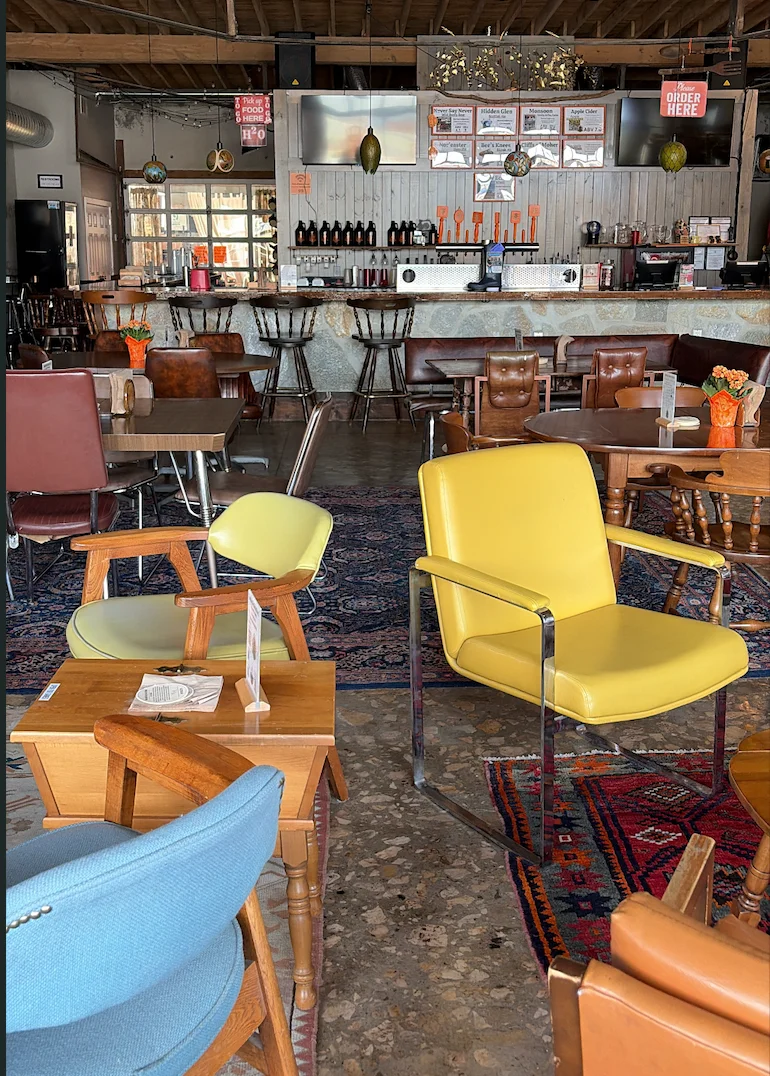 Eclectic restaurant interior with colorful vintage chairs and a rustic bar