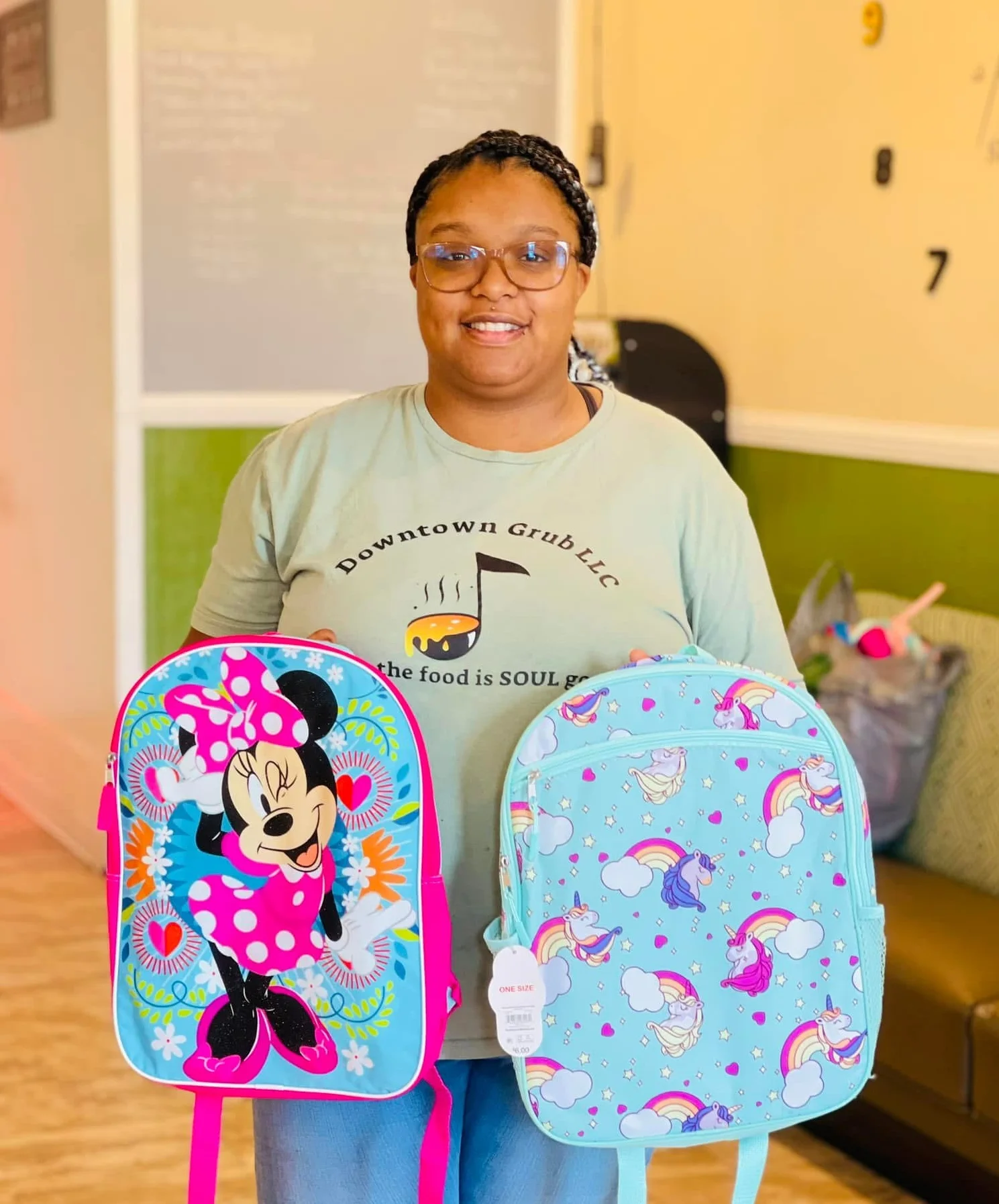 Woman holding colorful children's backpacks in a cozy restaurant setting