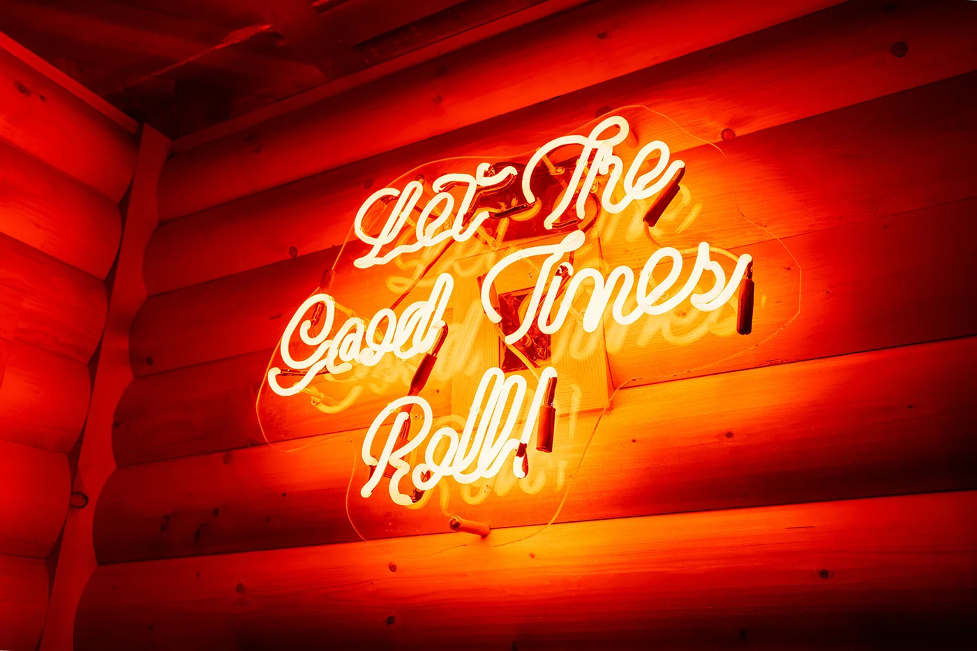Neon sign saying 'Let The Good Times Roll' in a cozy restaurant