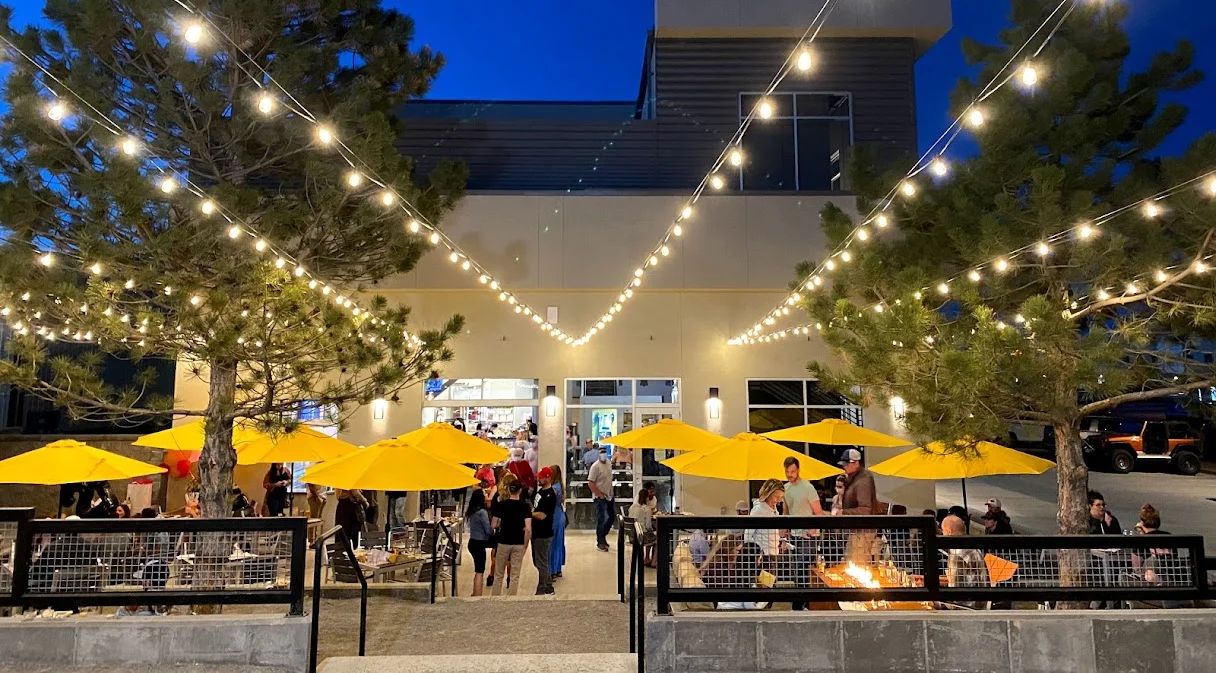 Outdoor dining area with yellow umbrellas and string lights at night