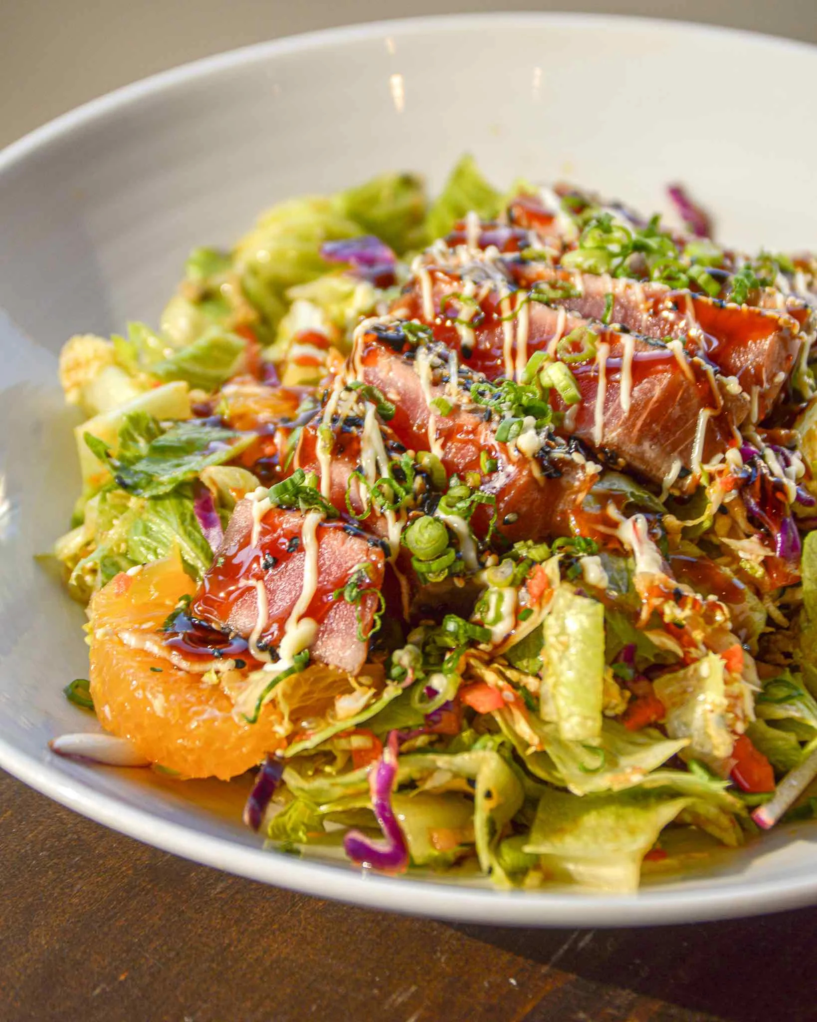 Ginger Soy Tuna Salad sits in a windowsill with the sun on it, you can see mandarin oranges and tuna on the top