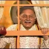 Smiling elderly man looking through a window with curtains