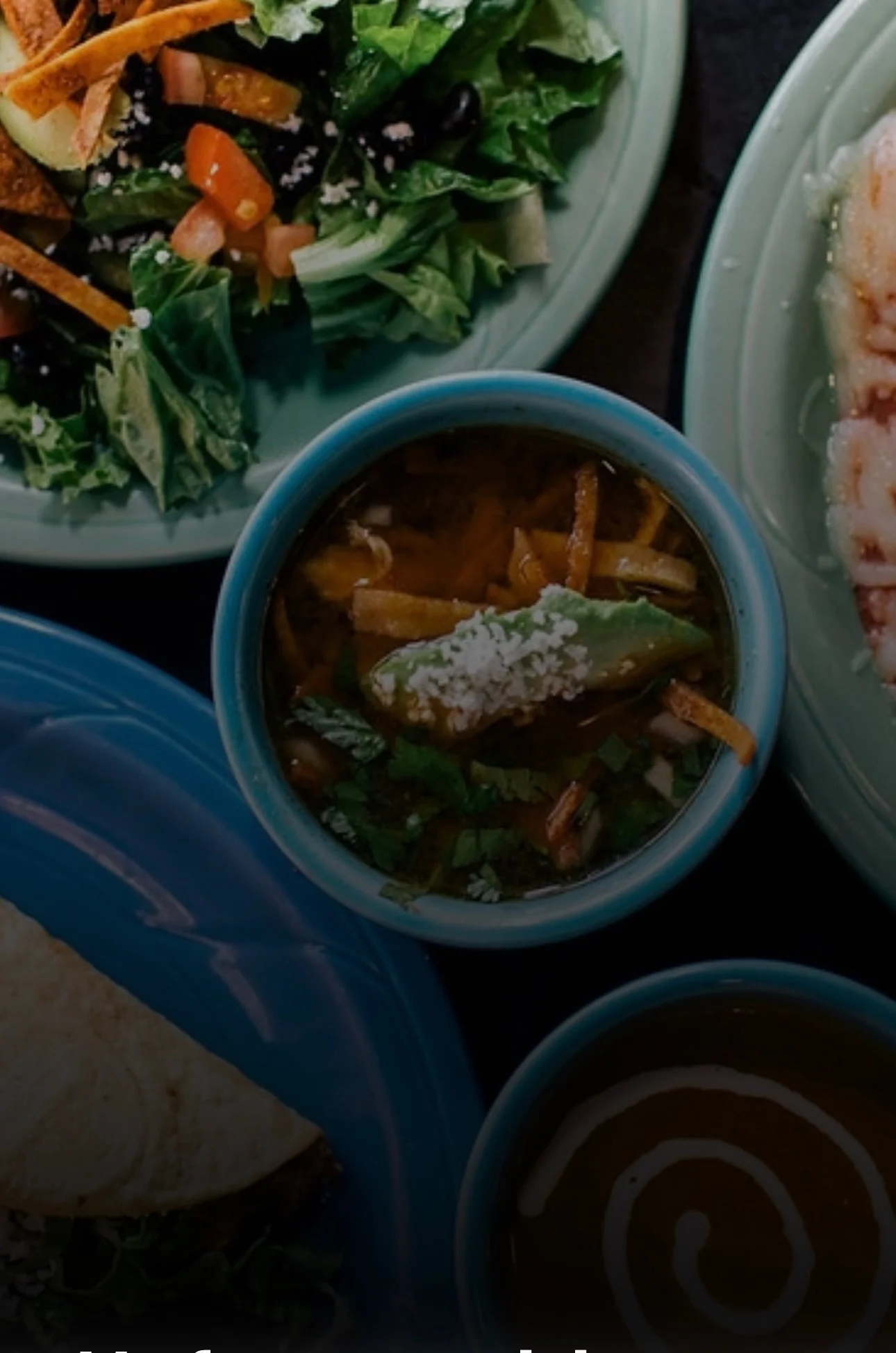 A vibrant assortment of food featuring a bowl of soup topped with avocado and tortilla strips, accompanied by a fresh salad.
