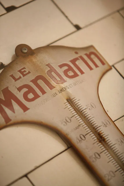 Vintage thermometer with 'Le Mandarin' branding on tiled background