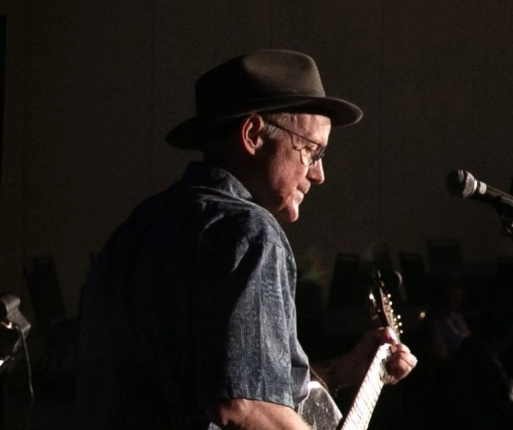 Musician playing guitar on stage with dramatic lighting