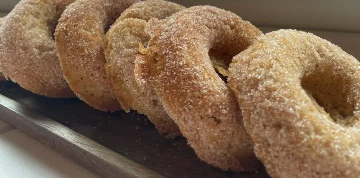 Freshly baked cinnamon sugar donuts on a wooden platter