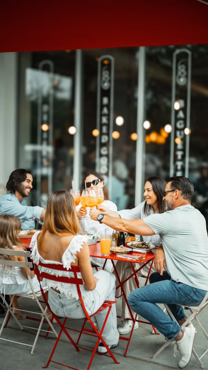 Group of friends toasting with cocktails at a vibrant outdoor restaurant