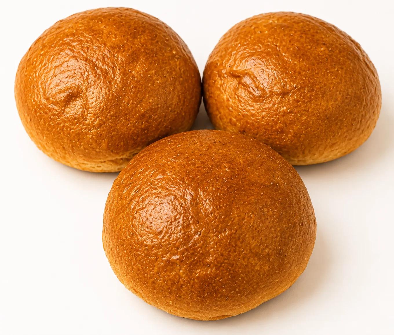 Three golden-brown, round bread rolls arranged closely together.