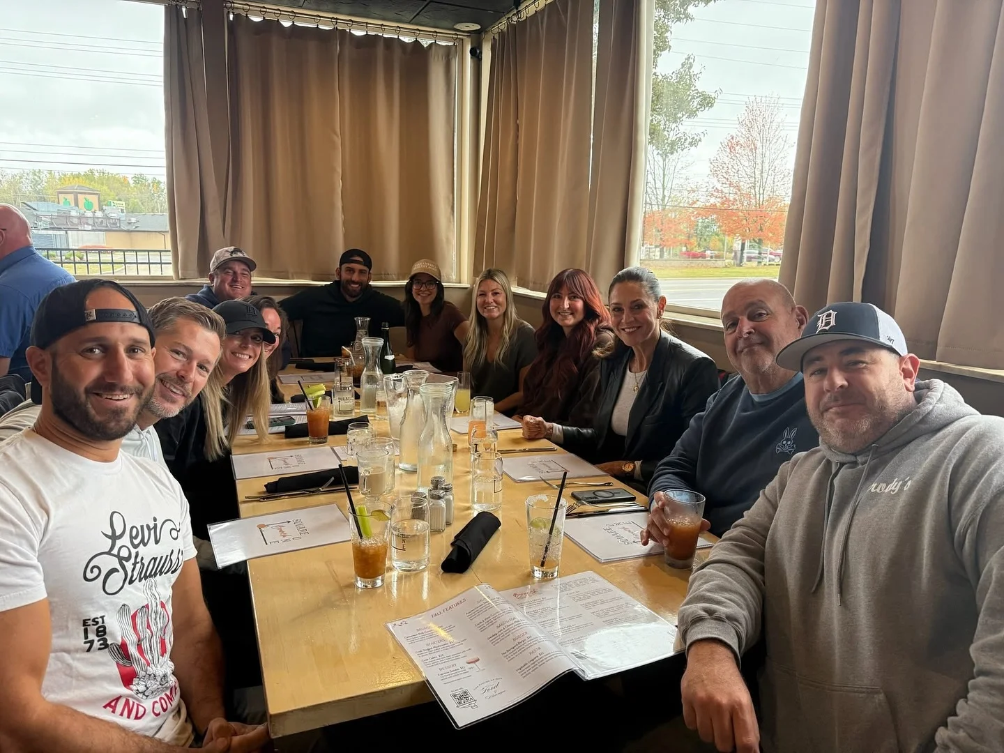 A lively dining table filled with a group of people enjoying a meal together, surrounded by drinks and menus.