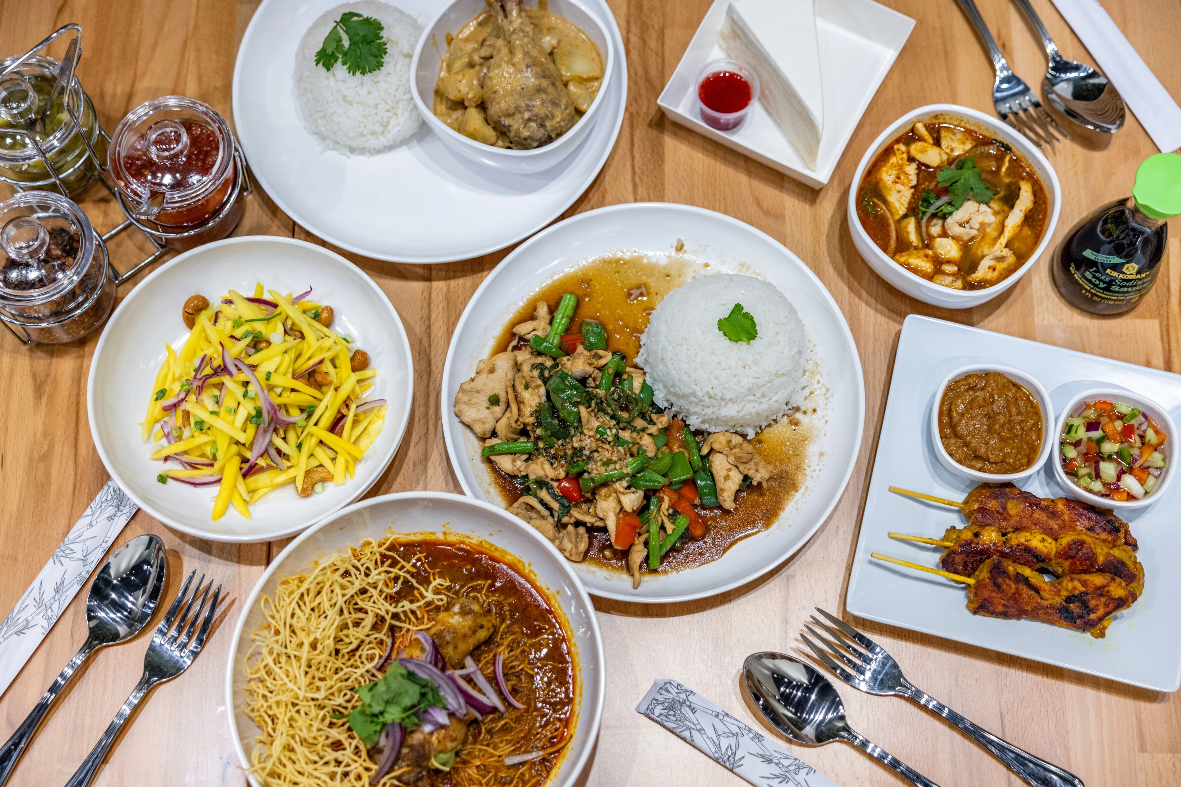 Assorted Thai dishes including curry, satay, and mango salad