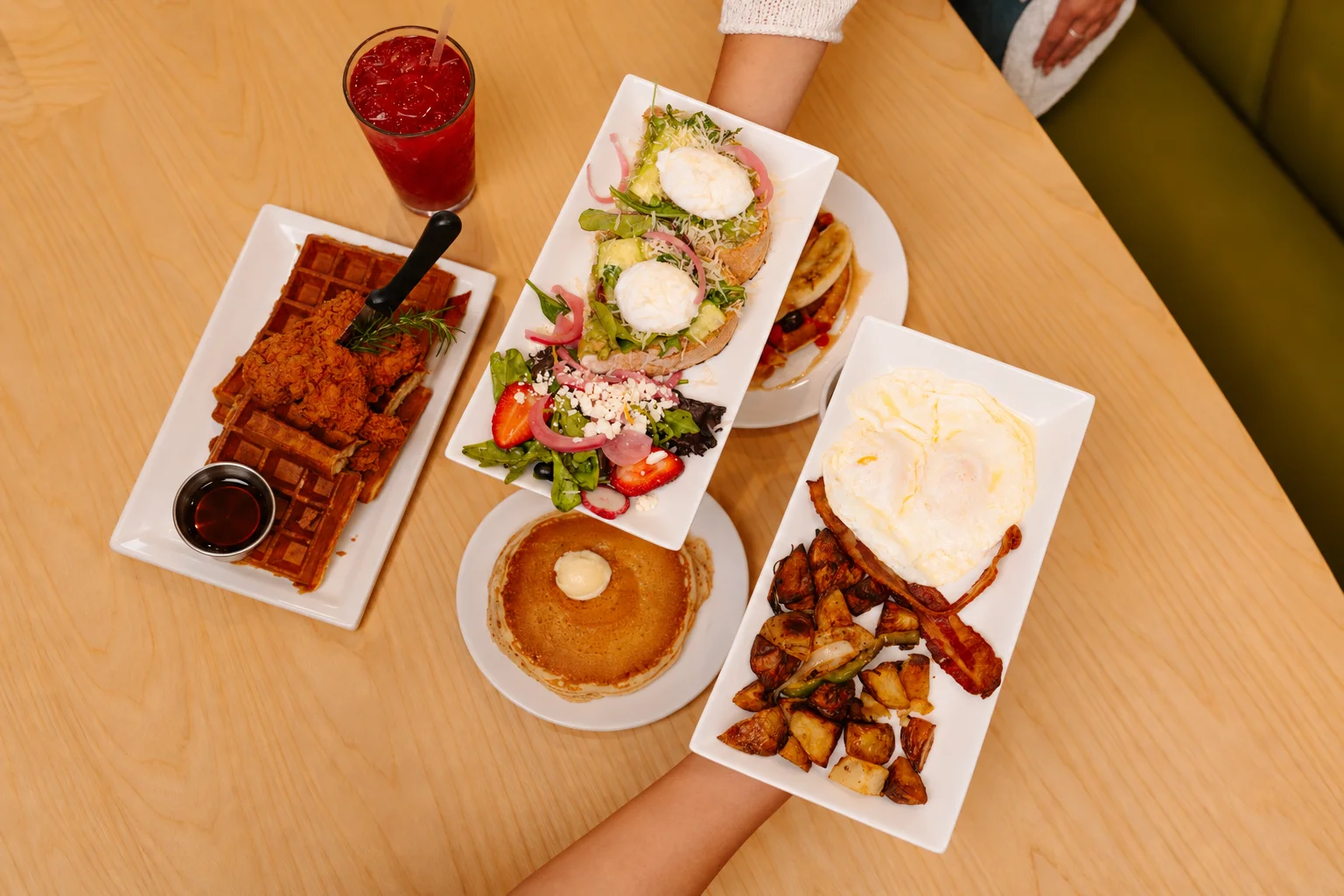 Southern brunch spread with chicken and waffles, avocado toast, pancakes, eggs, bacon, and potatoes