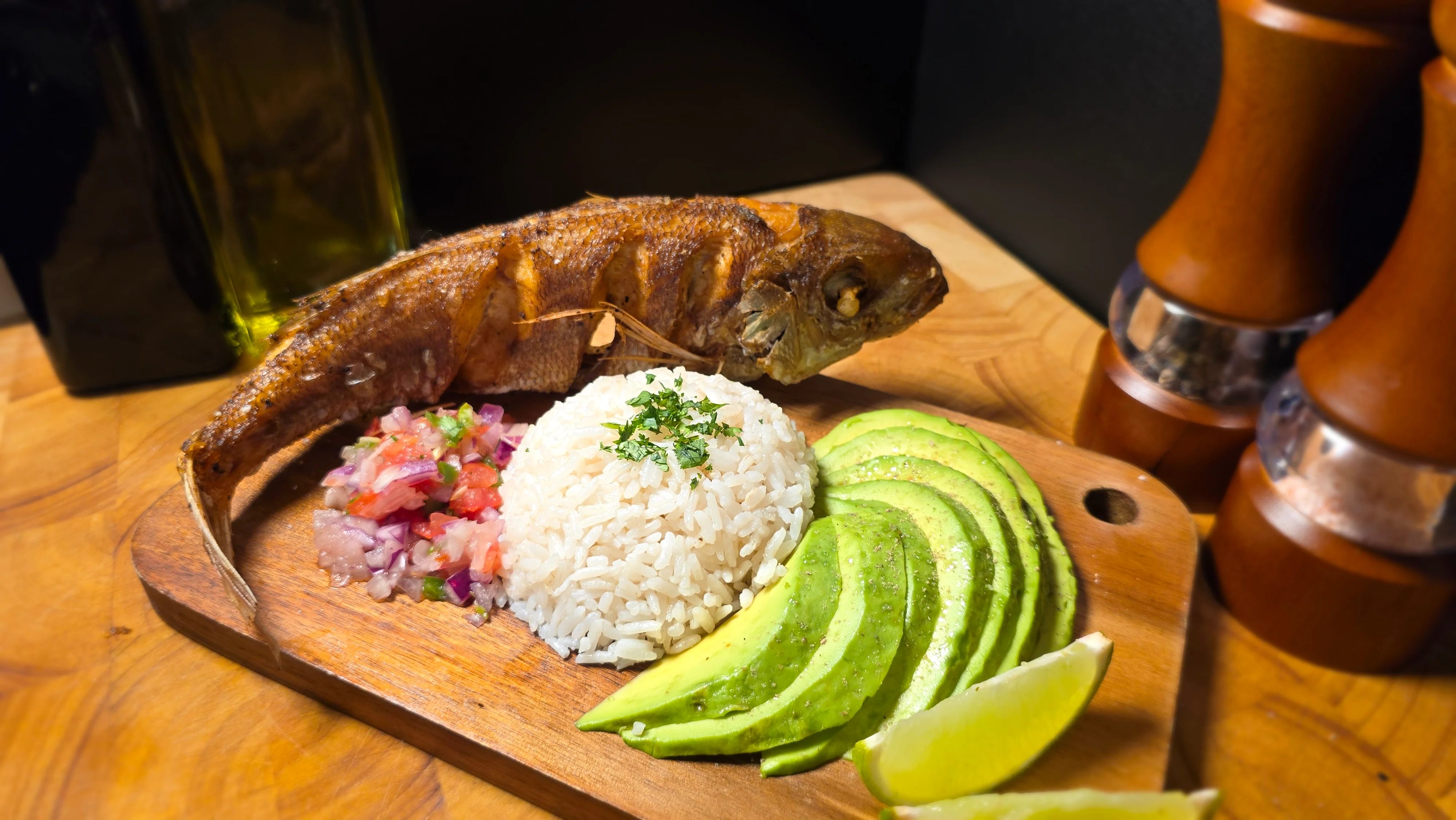Crispy whole fried fish with rice and avocado, a traditional Latin American dish