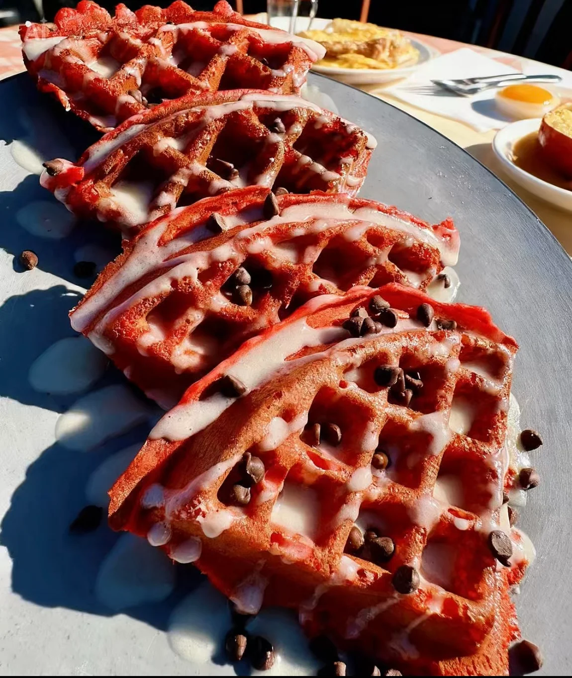 Red velvet waffles drizzled with icing and chocolate chips