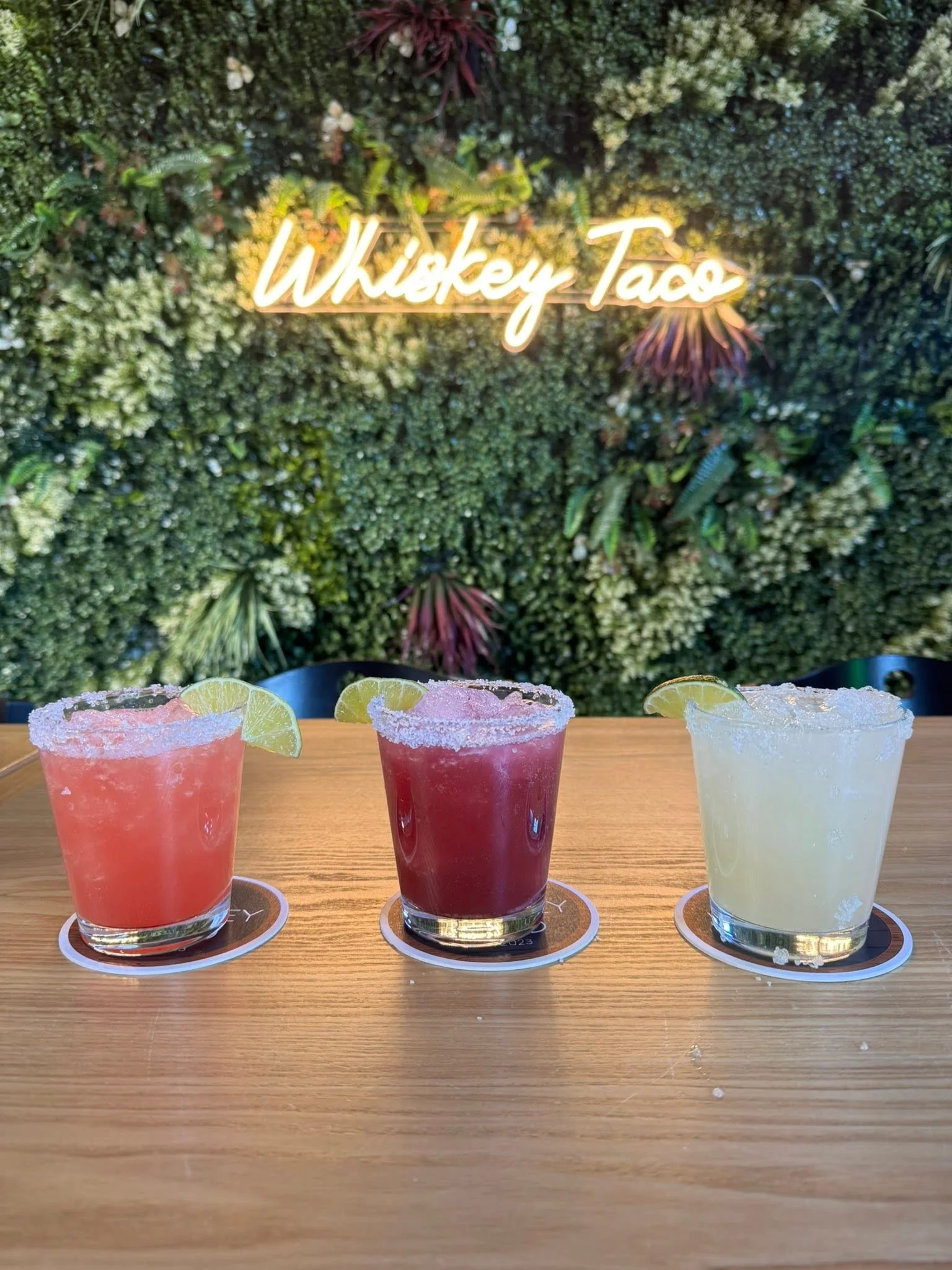 Colorful margaritas on a wooden table at Whiskey Taco restaurant