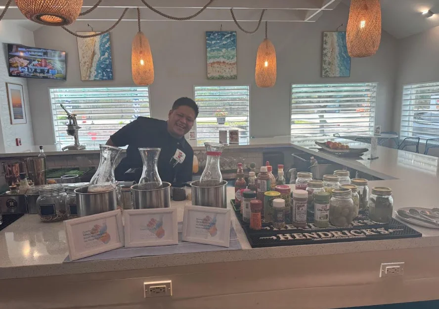 Bartender smiling at a vibrant cocktail bar with various ingredients