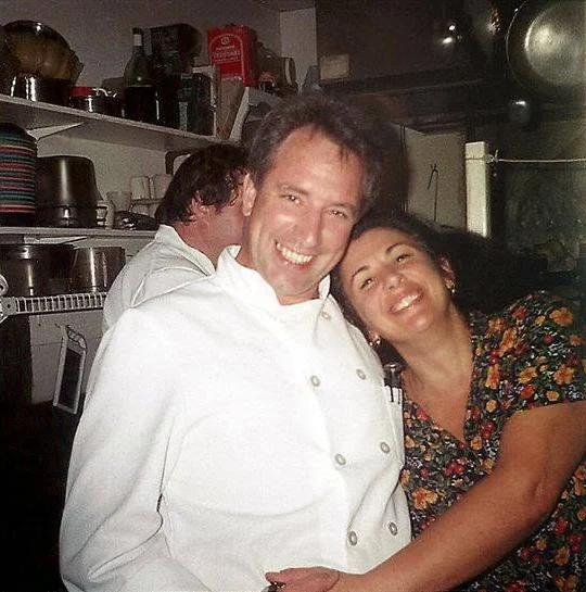 Chefs smiling together in a bustling restaurant kitchen