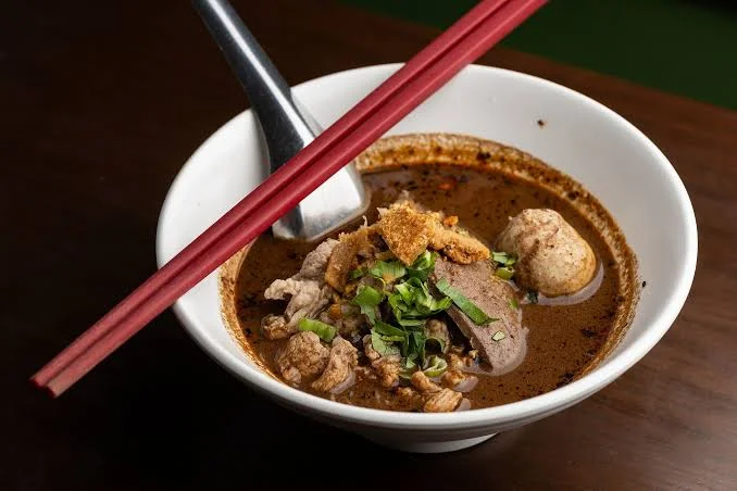 Bowl of Thai boat noodles with beef and herbs
