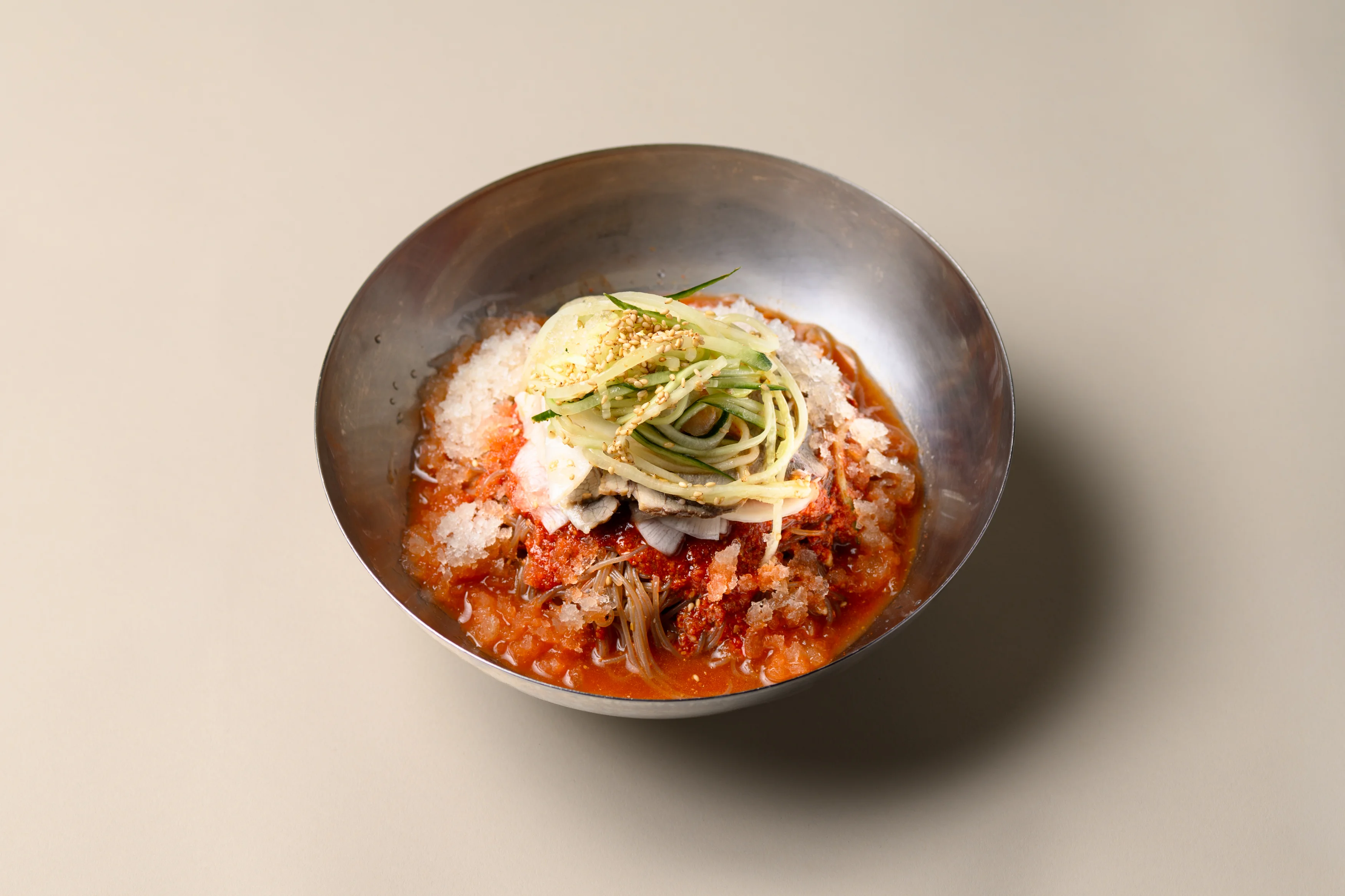 Korean bibim naengmyeon with spicy sauce, icy broth, beef, and cucumber