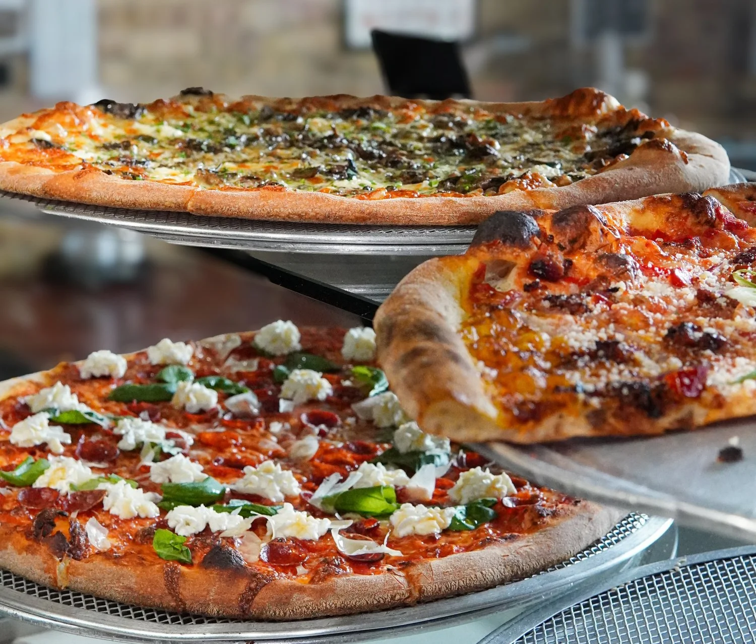 Three delicious pizzas displayed in a pizzeria