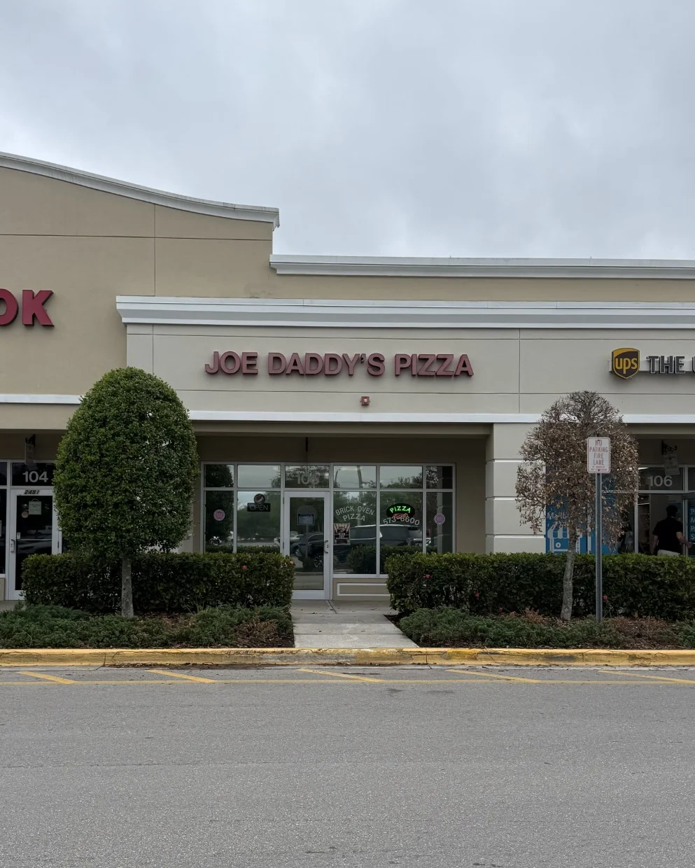 Exterior view of Joe Daddy's Pizza restaurant with signage and neighboring businesses
