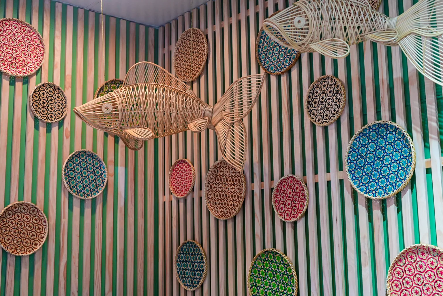 Artistic wall decor featuring woven fish and colorful circular patterns