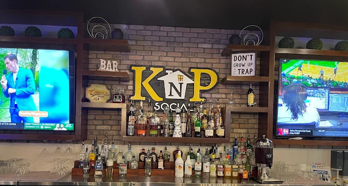 Bar area with liquor bottles and TVs displaying sports events.