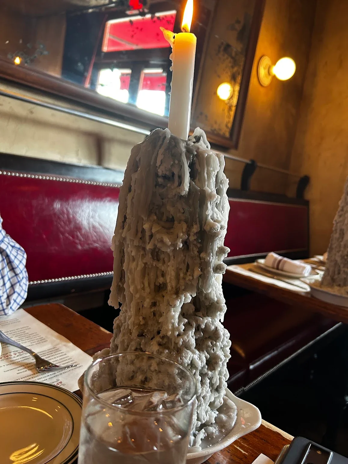 Unique candle centerpiece with wax drippings in a cozy restaurant setting