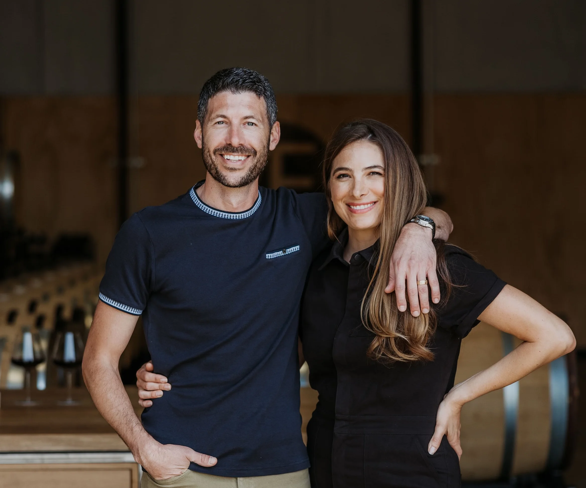Couple smiling together in a vineyard setting.