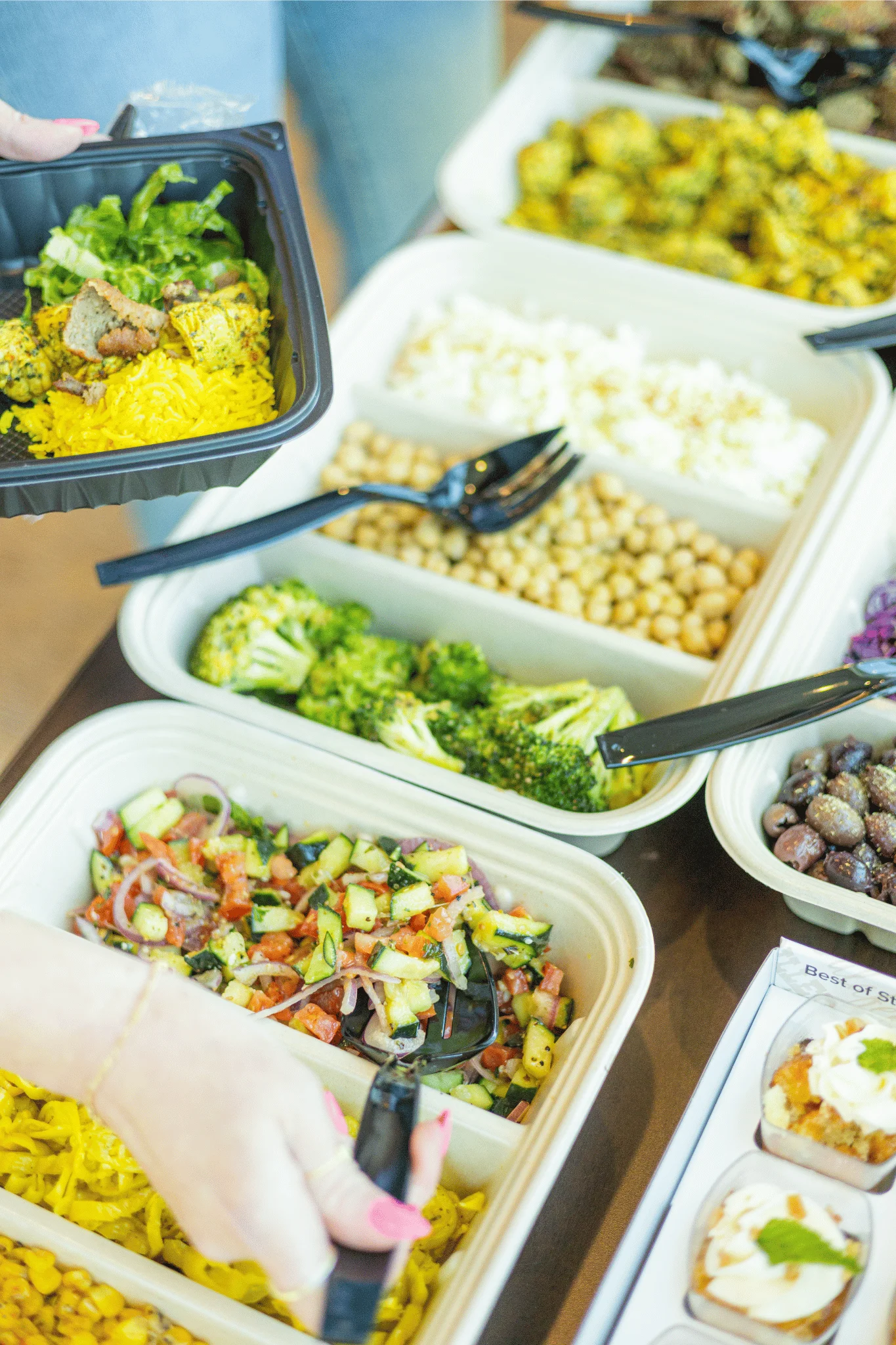 Catering trays of fresh salad and vegetable sides from Santorini's Greek Grill, part of the a la carte catering menu.