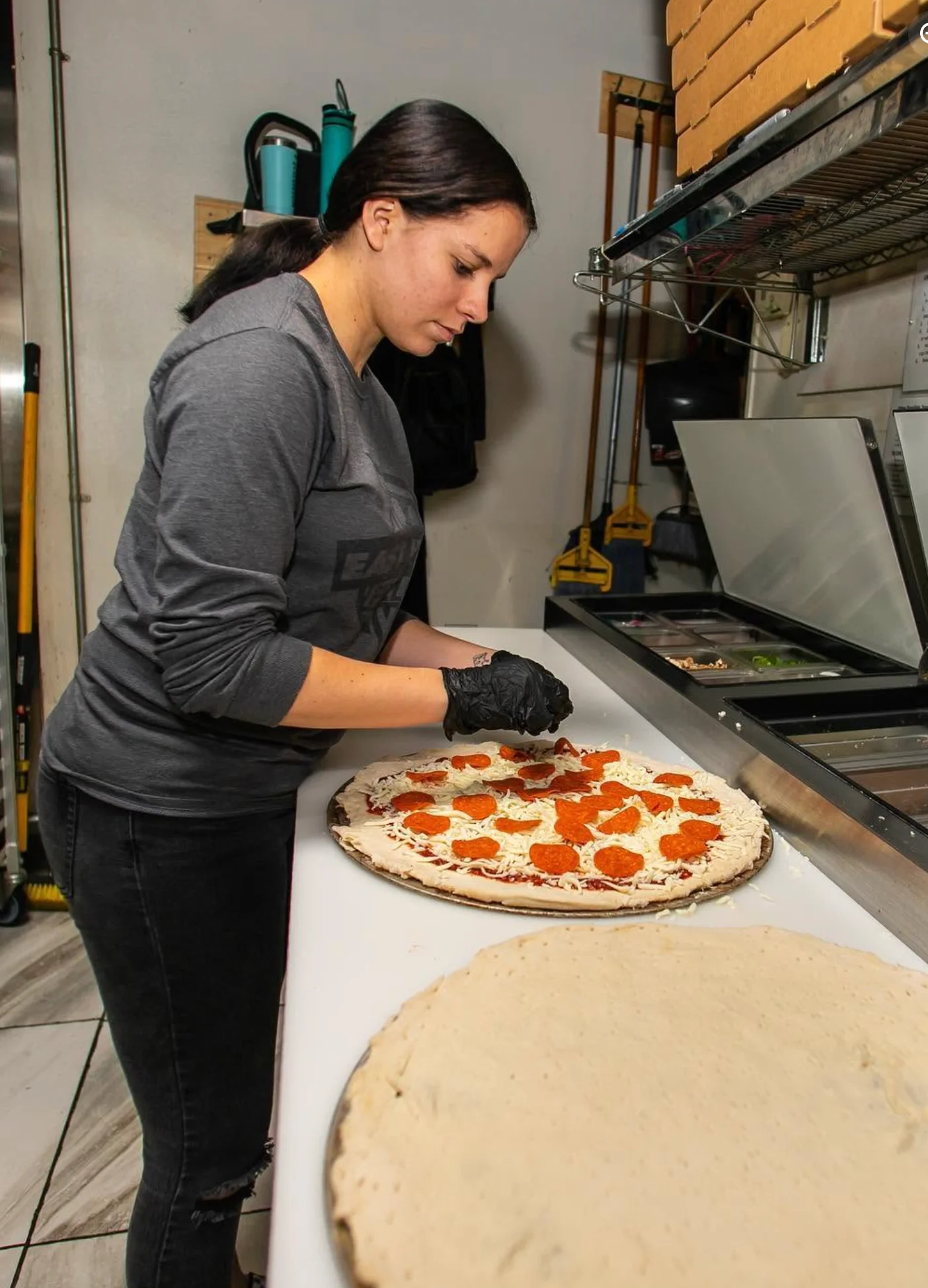 Worker preparing a pepperoni pizza in a restaurant kitchen