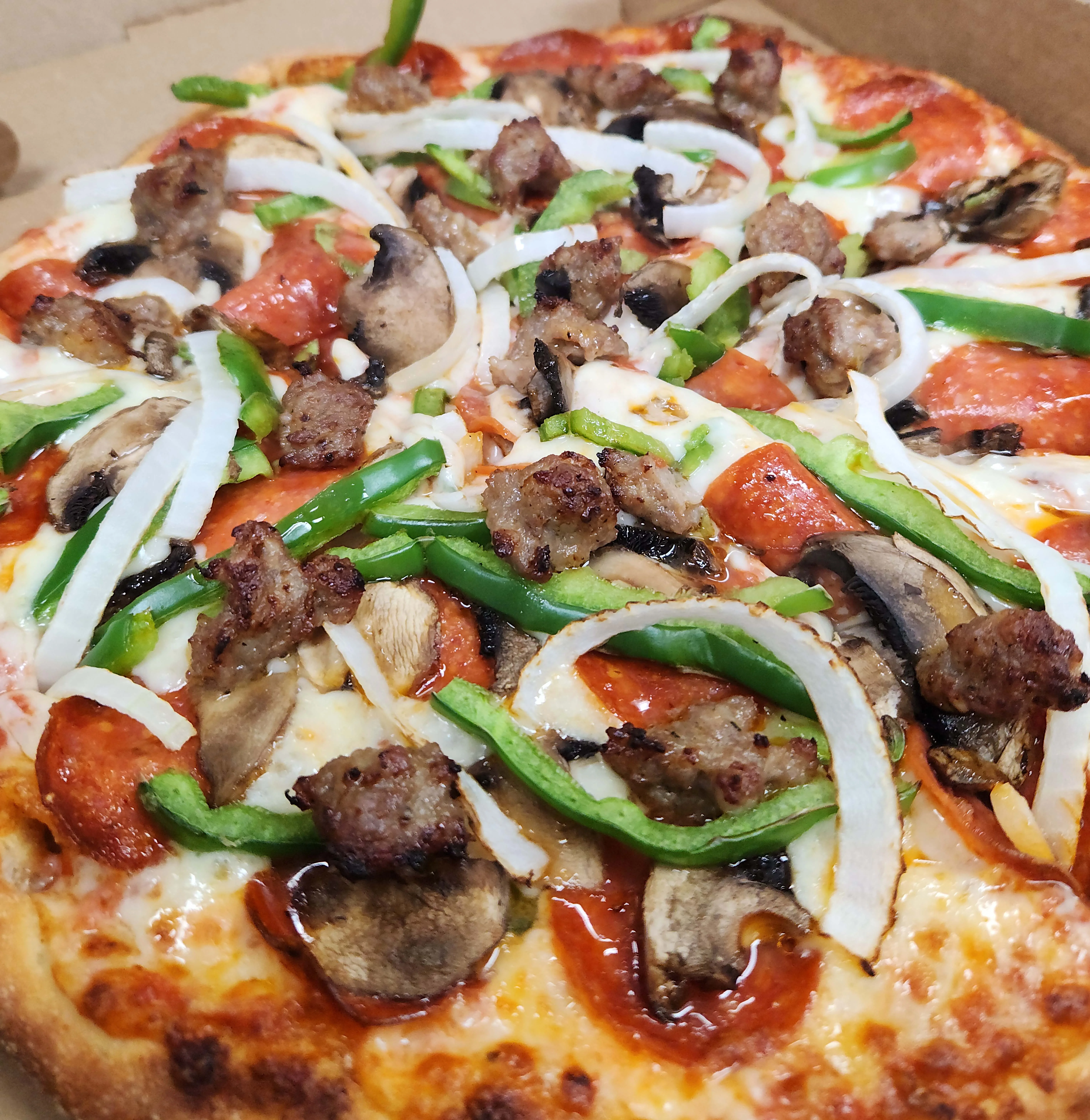 Delicious pepperoni and sausage pizza with green peppers and onions