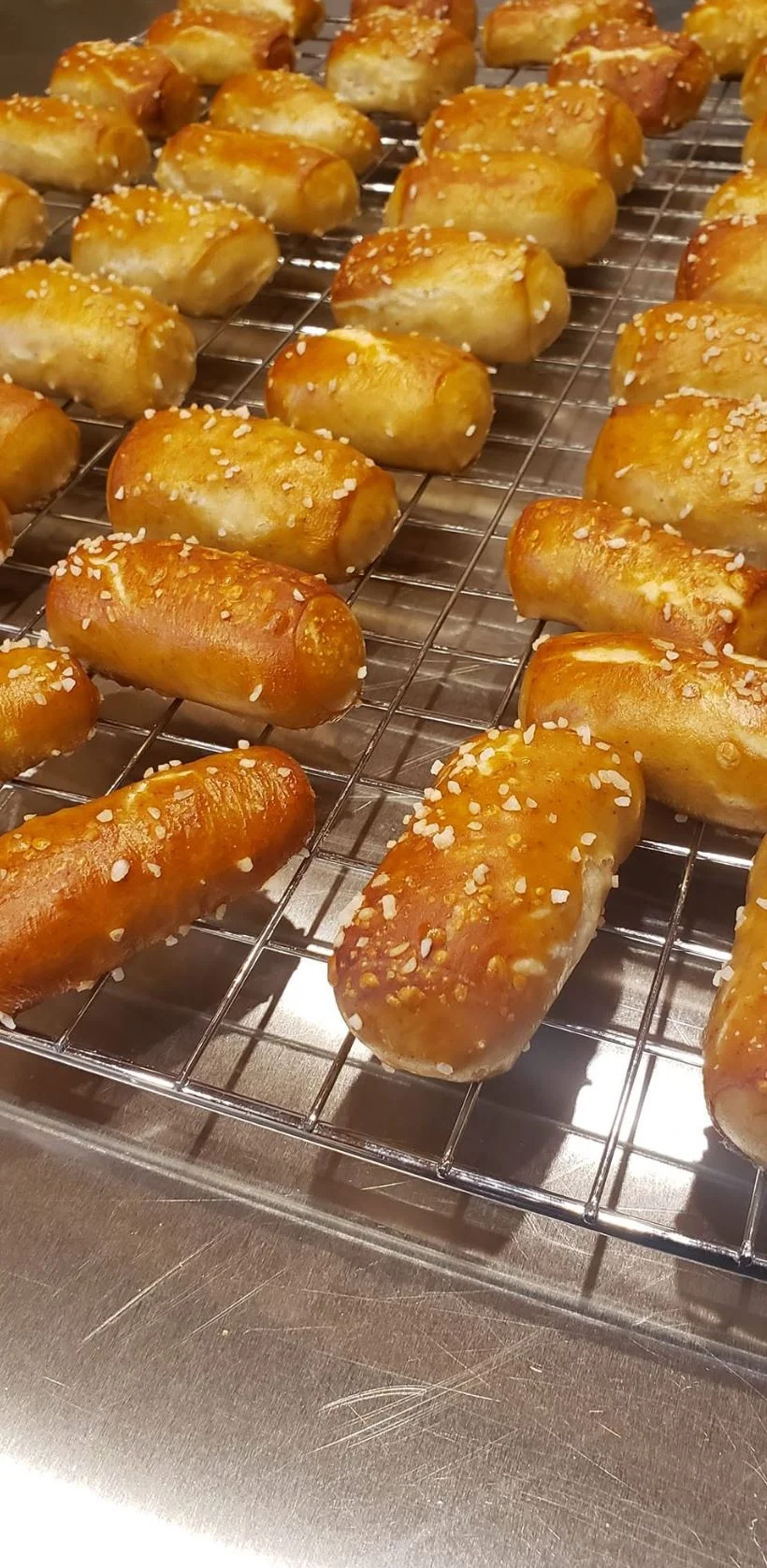 Freshly baked pretzel bites with sesame seeds on a cooling rack