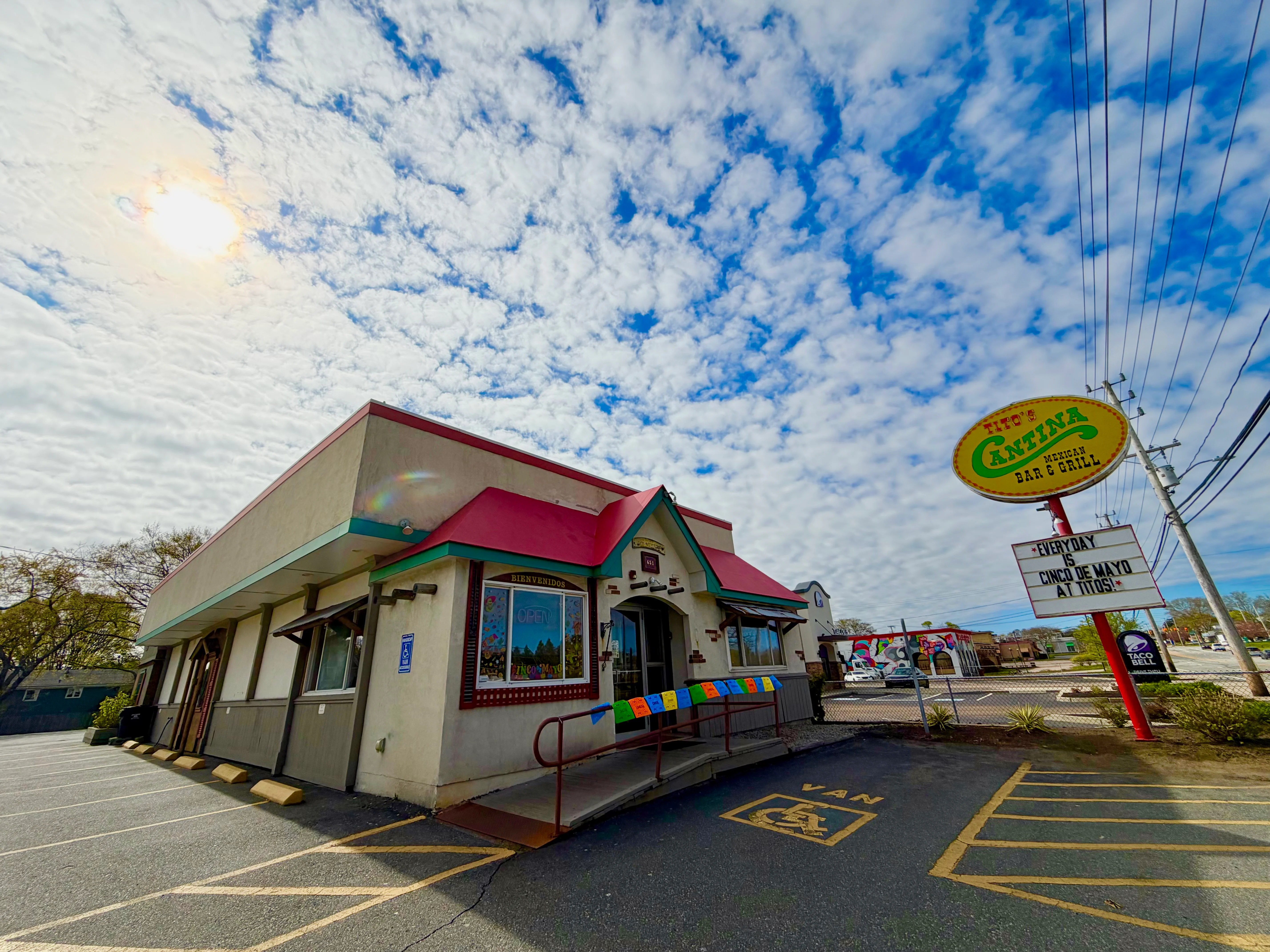 Exterior view of a vibrant Mexican restaurant with colorful signage and clouds above