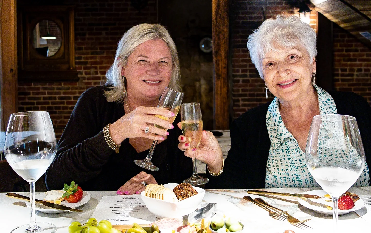 Two women toasting with champagne glasses in a cozy restaurant setting
