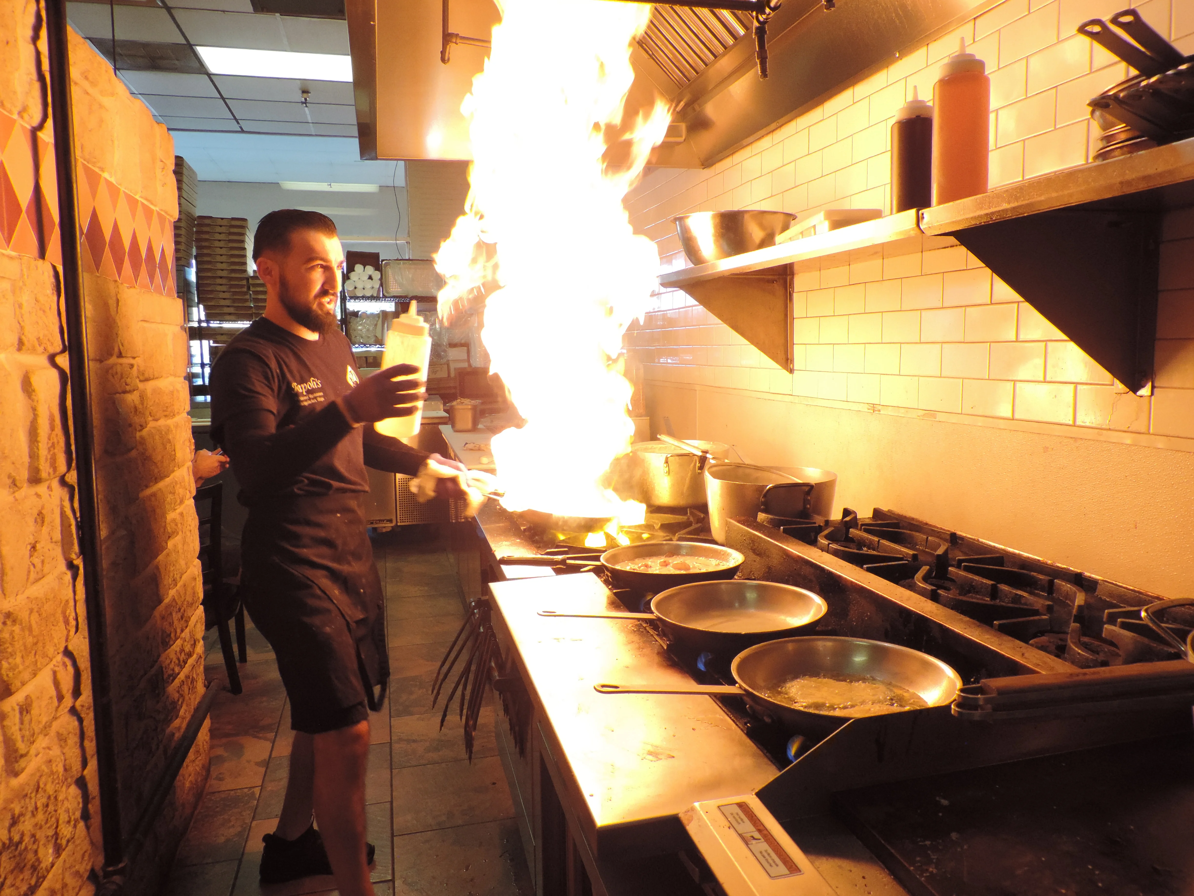 A chef is handling order tickets in a restaurant kitchen, preparing to serve orders.