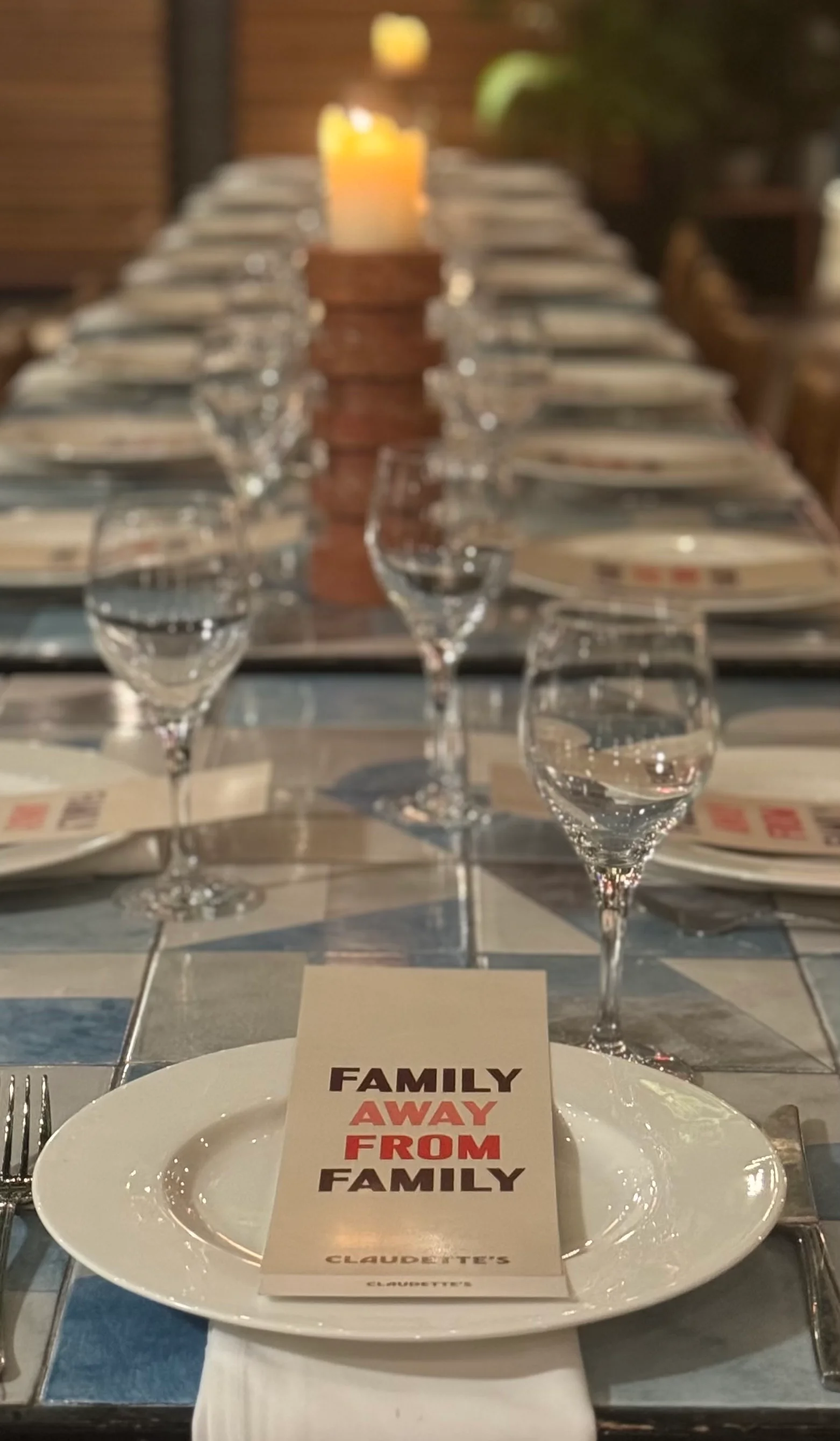 Picture of a Menu on a communal table at the Rockaway Hotel. The Menu says "Family Away From Family" with a Claudette's logo at the bottom.