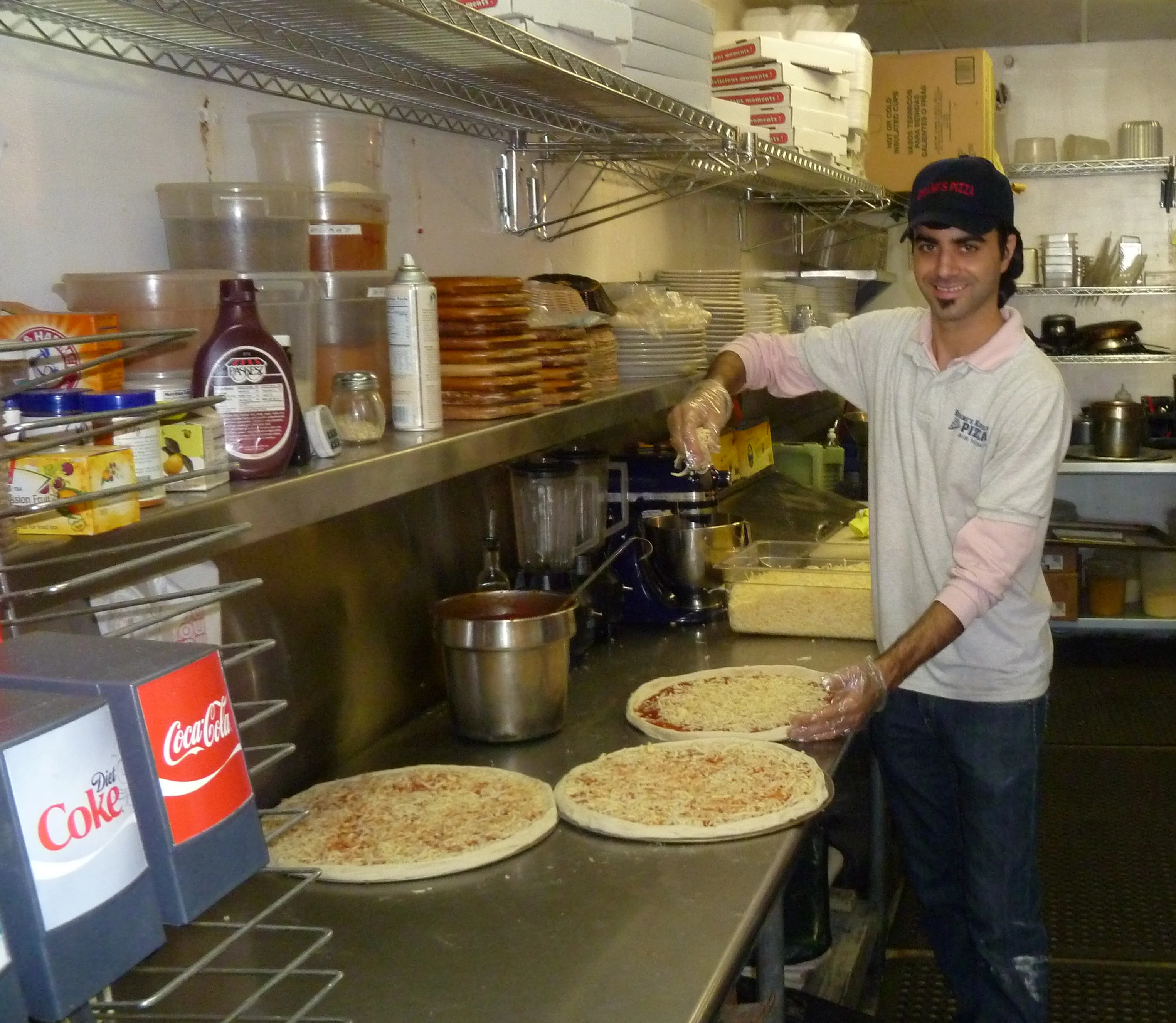Pizza preparation in a bustling restaurant kitchen