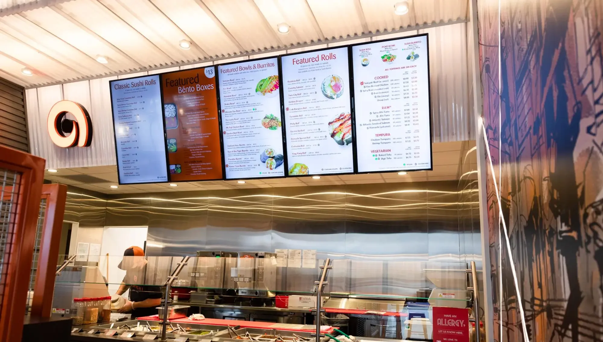 Modern sushi restaurant counter with menu boards and food preparation station