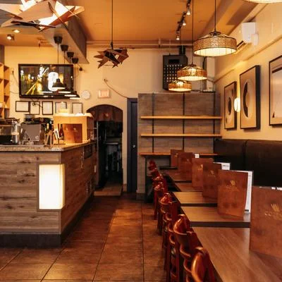 An inviting restaurant interior showcasing a bar area, modern lighting, and neatly arranged tables with menus.