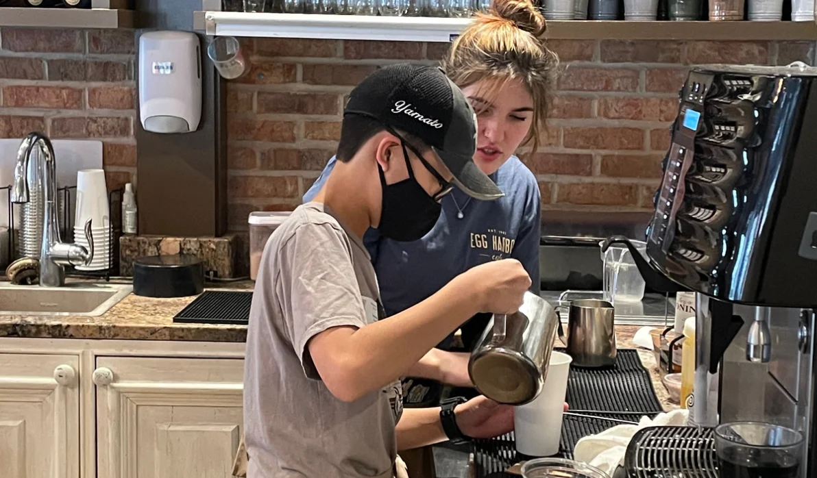 Barista teaching a young apprentice at a coffee shop