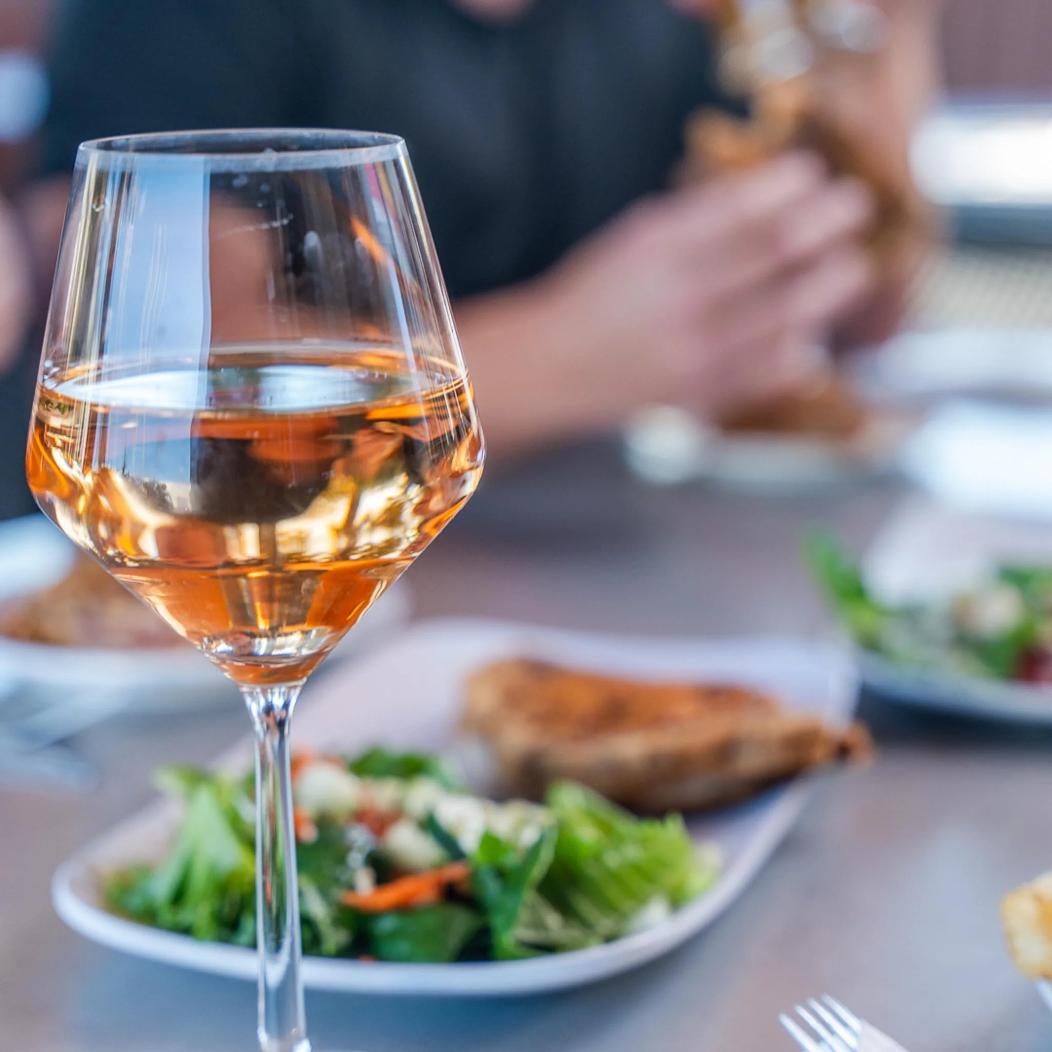 Glass of rosé wine with a fresh salad and crispy chicken on a dining table