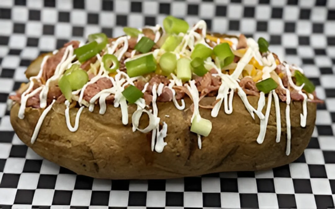 A loaded baked potato with chives and meat