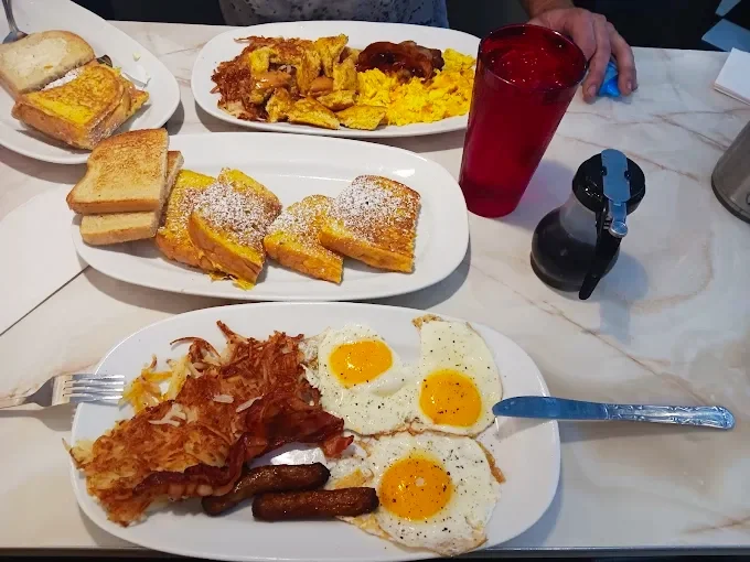 Moonlite Diner breakfast spread featuring sunny-side-up eggs, bacon, sausage, crispy hash browns, French toast, scrambled eggs, and toast served family-style.